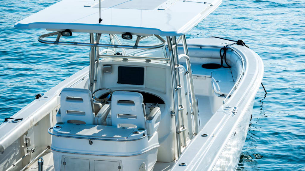 Open white motorboat with two seats, steering console, and roof, floating on clear blue water.